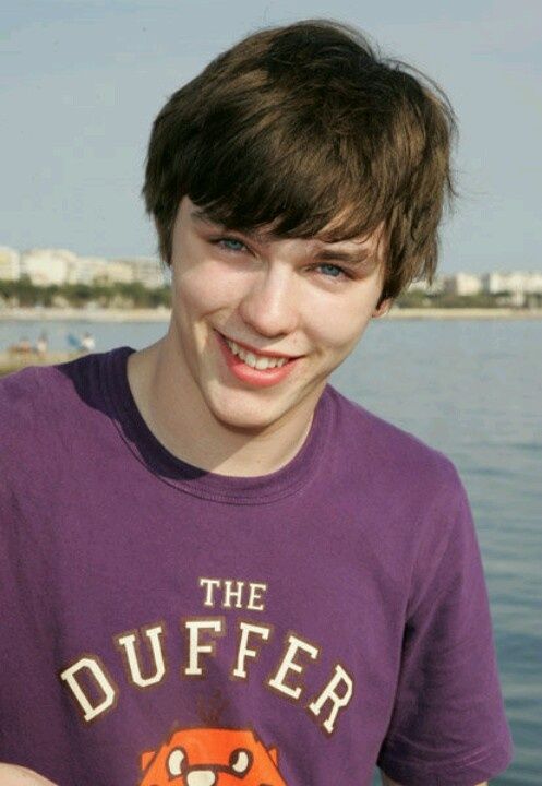 a young boy is smiling while holding a frisbee in his hand and looking at the camera