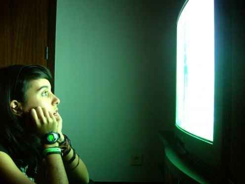 a woman sitting in front of a tv with her hand on her face looking at the screen