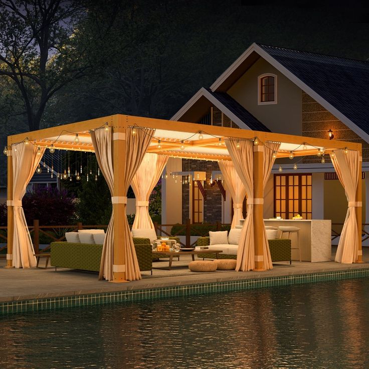 a gazebo sitting next to a body of water in front of a house at night