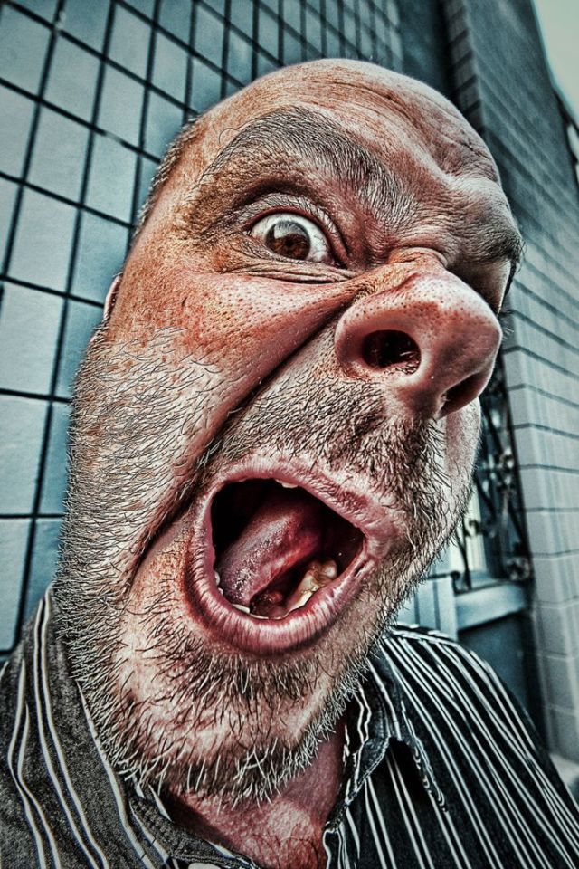 an old man with his mouth open in front of a tiled wall