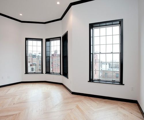 an empty room with three windows and wood flooring on either side of the wall