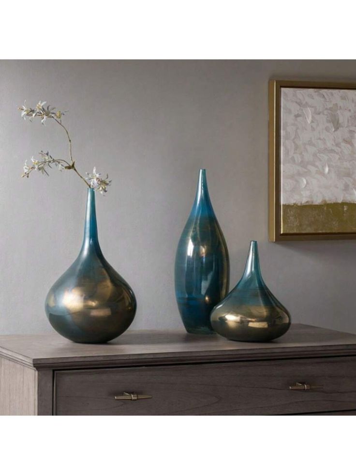 three blue vases sitting on top of a dresser