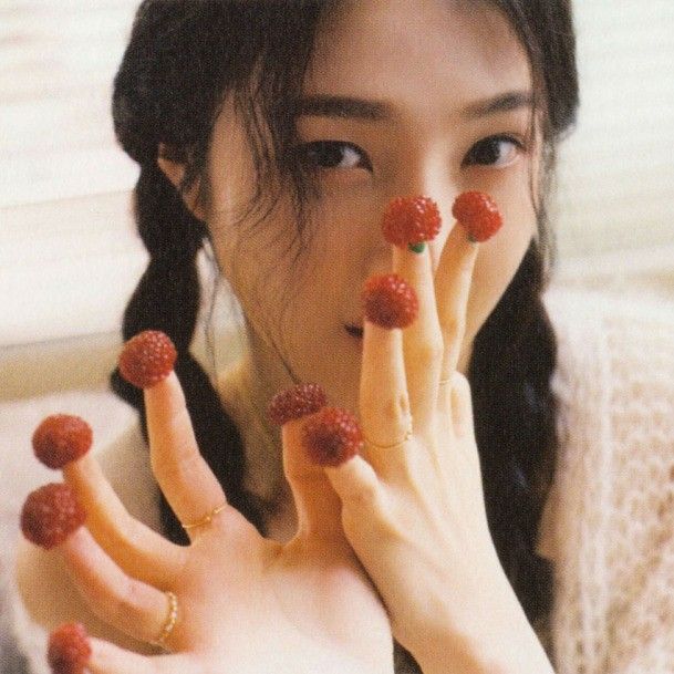 a woman holding her hands up to her face with raspberries all over her fingers