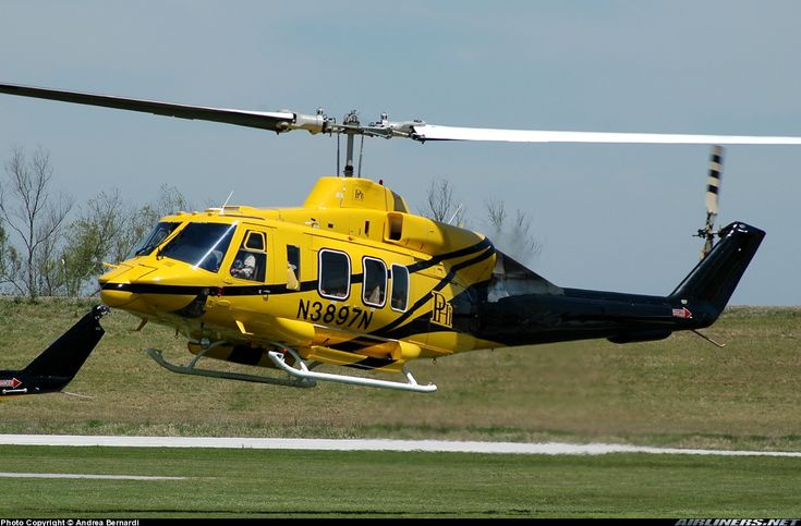 a yellow helicopter is flying low to the ground