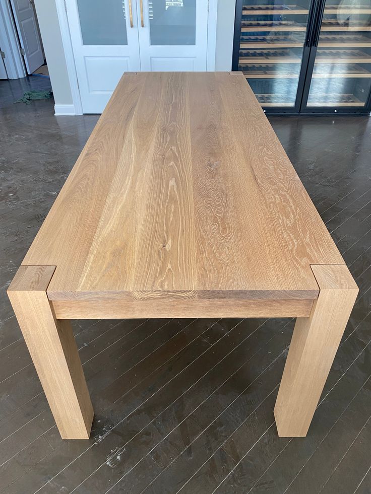 a wooden table sitting on top of a hard wood floor next to a glass door