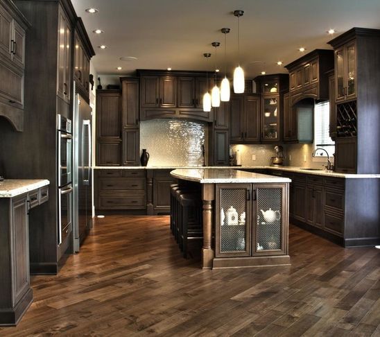 a large kitchen with wooden floors and dark wood cabinets, along with stainless steel appliances