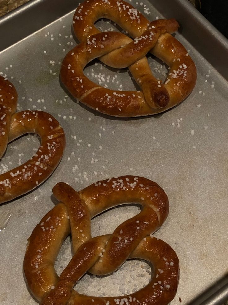 three pretzels sitting on top of a metal pan covered in powdered sugar