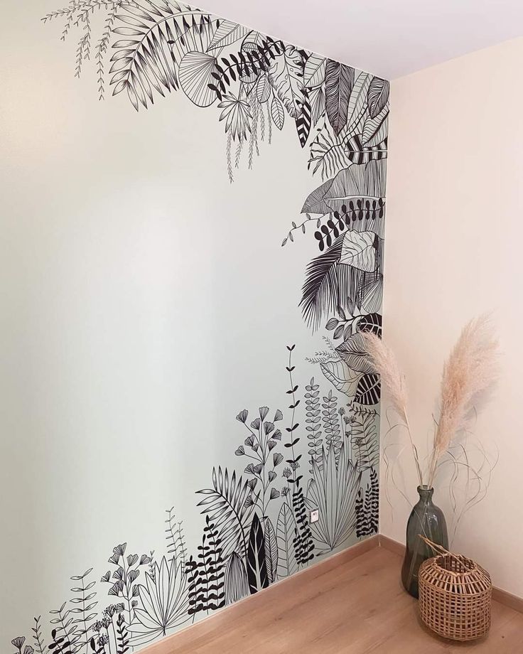 the wall is painted with black and white leaves on it, along with a plant in a wicker basket