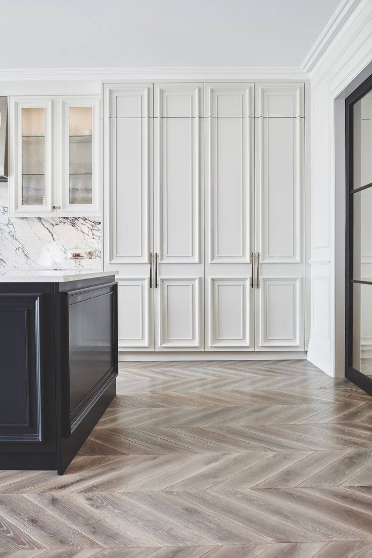 an empty kitchen with white cabinets and marble counter tops