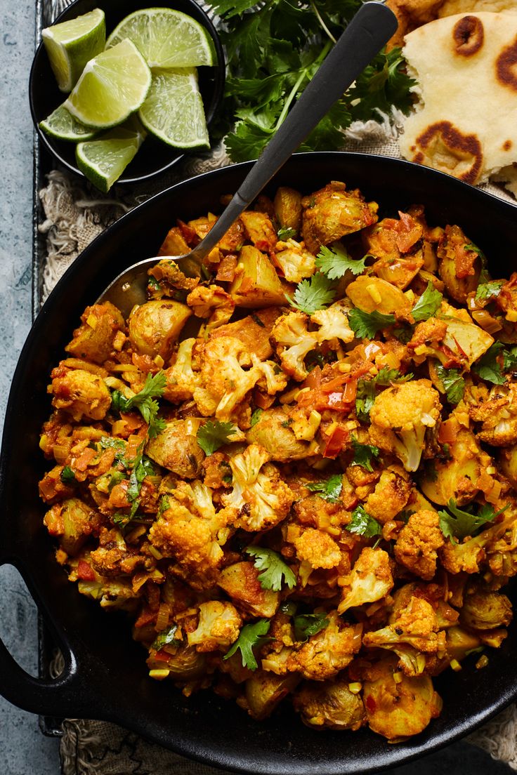 a skillet filled with cauliflower and other food on top of a table