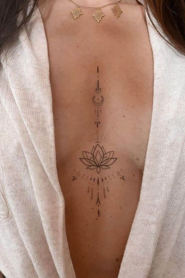 the back of a woman's chest with an arrow and lotus tattoo on it