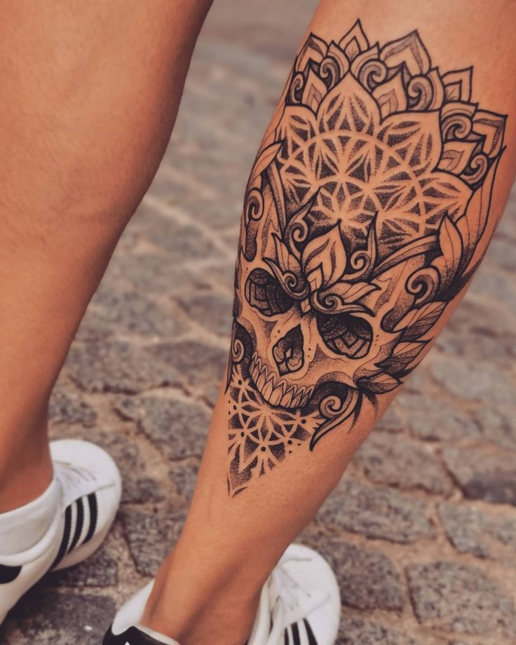 a woman's leg with a skull and flower tattoo design on the lower leg