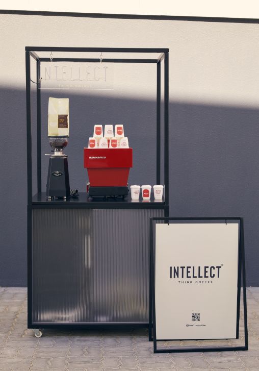 a coffee machine and some cups on a table next to a sign that says intelelect