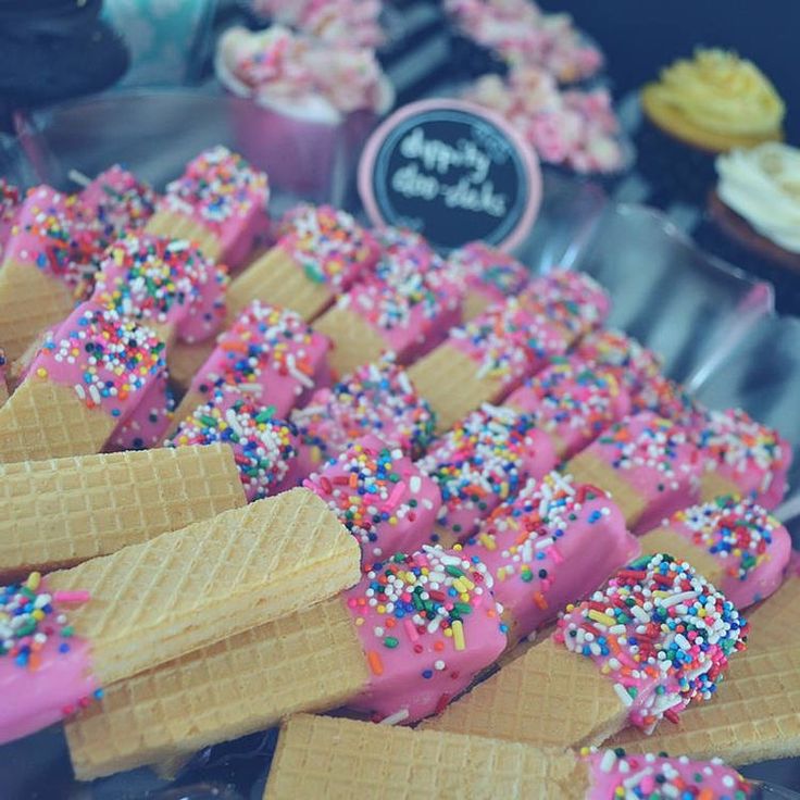 ice cream cones with sprinkles and pink frosting are on display in a bakery