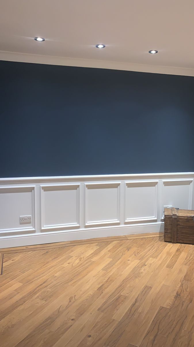 empty room with hard wood flooring and blue painted wall in the corner, next to a wooden crate