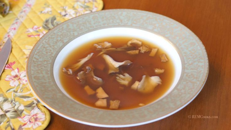 a bowl of soup is sitting on a table next to a knife and napkins