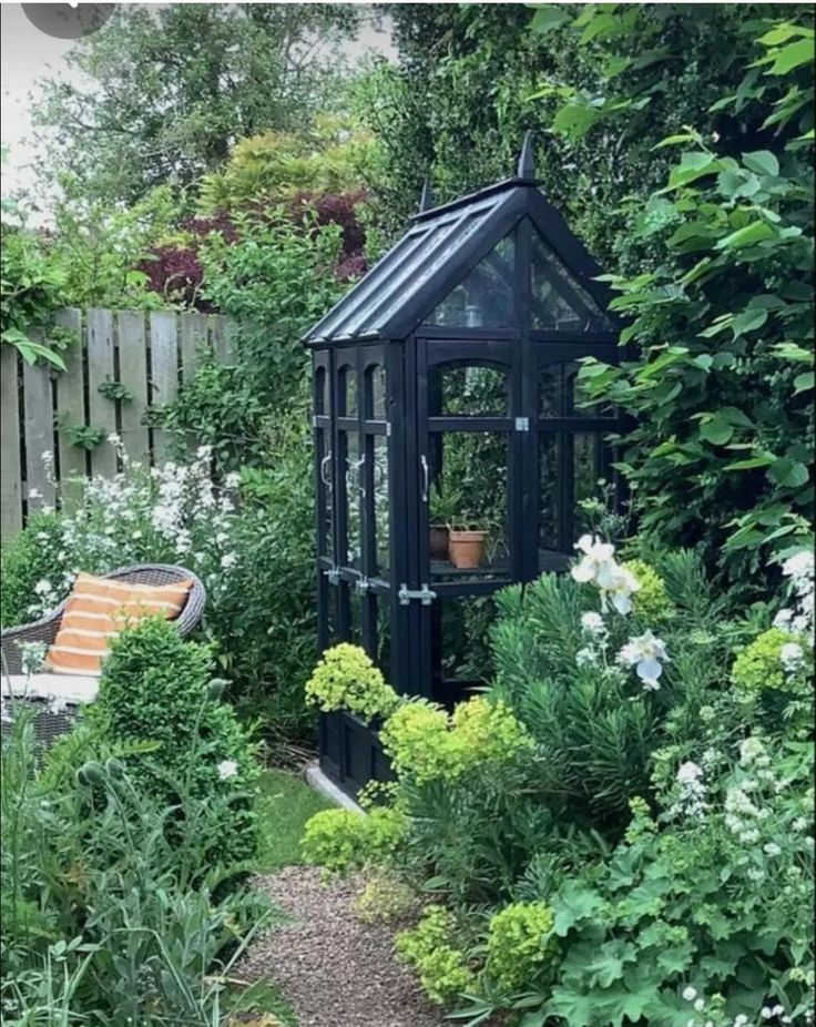 a small black gazebo surrounded by plants and flowers