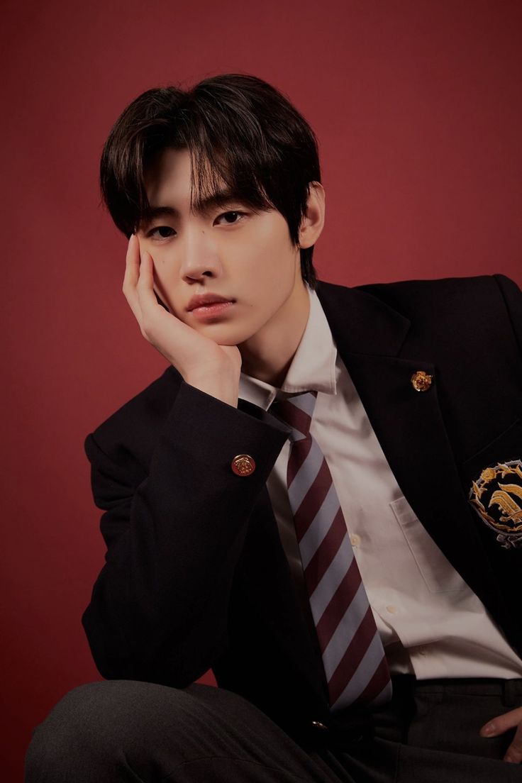 a young man in a suit and tie posing for a photo with his hand on his chin