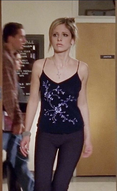 a woman is walking down the hall in tight black leggings and a tank top