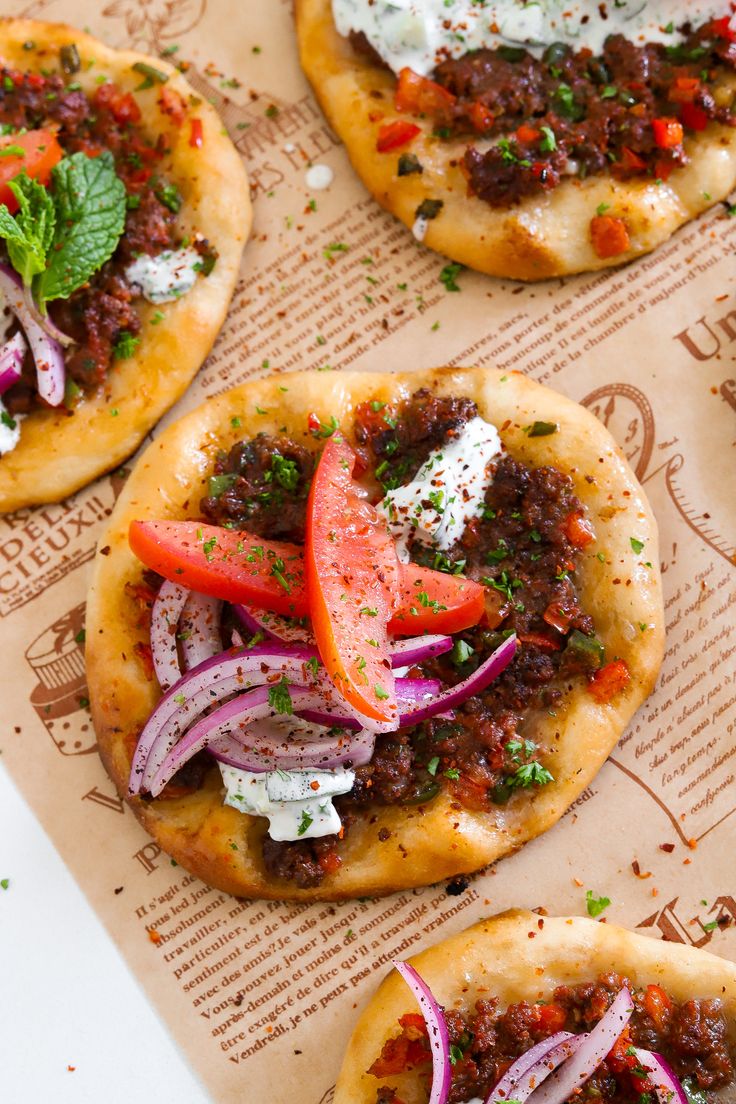 several flat bread pizzas with various toppings on top of paper wrapper, ready to be eaten