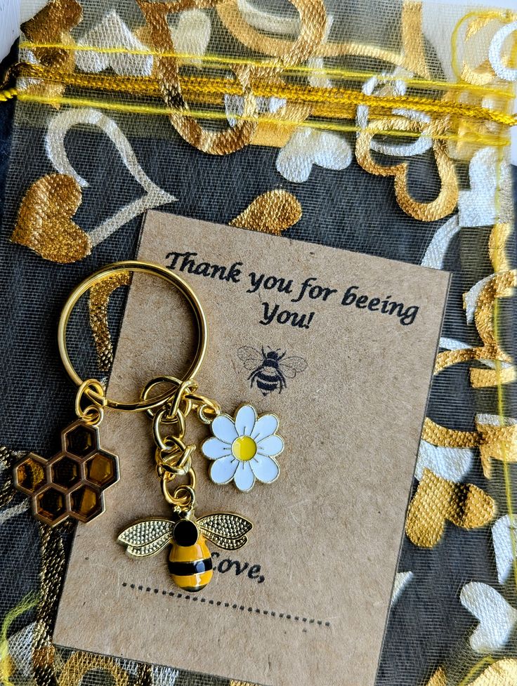 a thank card with a bee keychain attached to it and a flower on the front