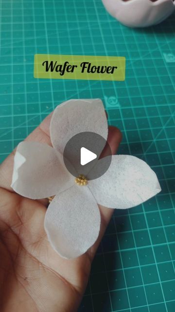 a person holding a flower on top of a cutting board