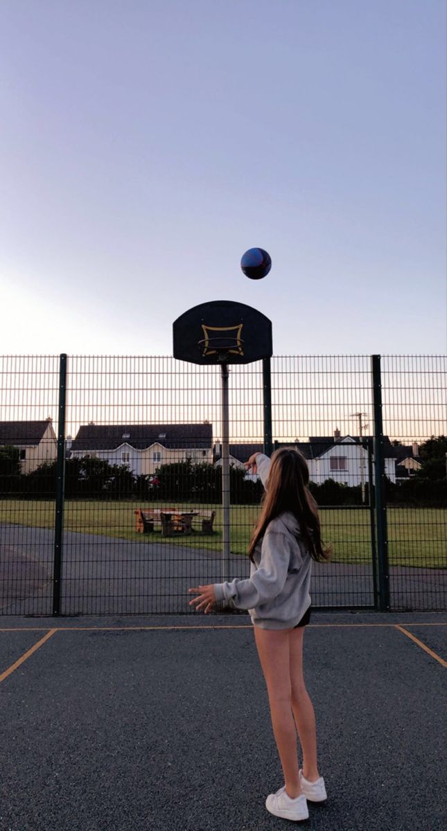 a girl is playing with a ball on the court