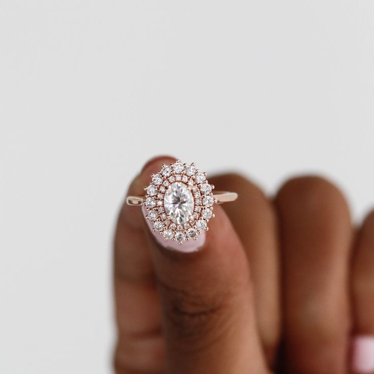 a woman's hand holding a ring with a diamond in the middle and an oval shaped center