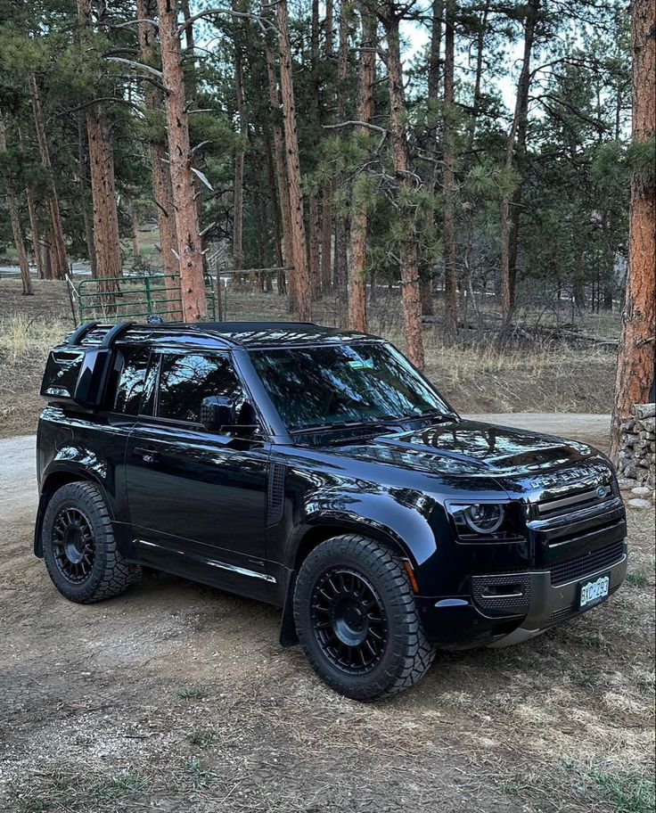 a black suv parked in front of some trees