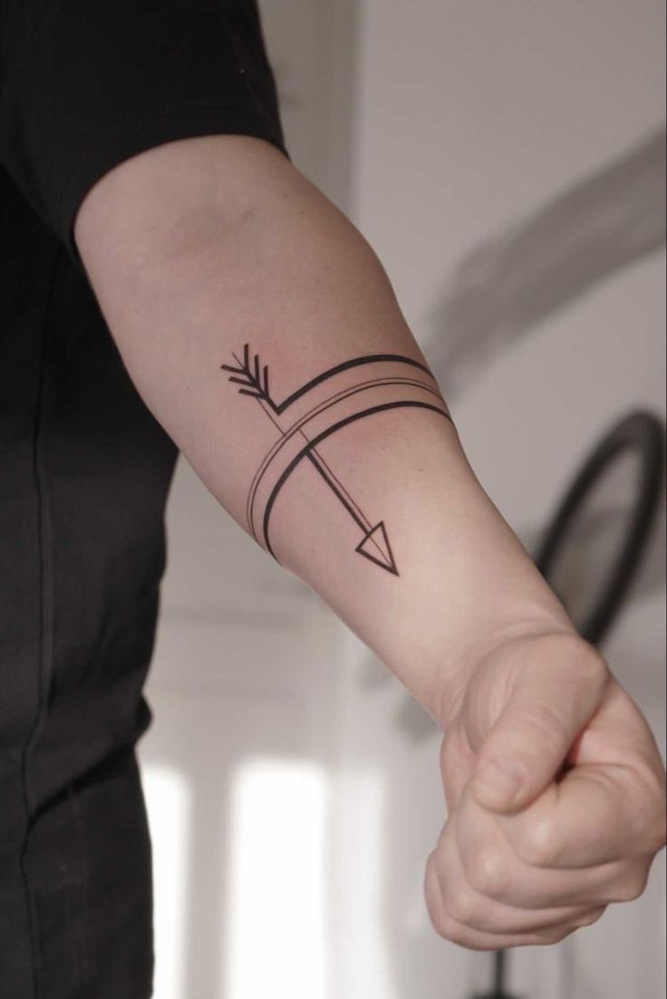 a person holding their arm with an arrow tattoo on the left side of his arm