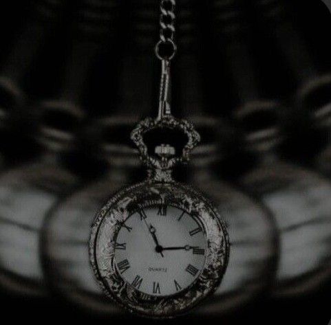 a black and white photo of an old pocket watch with chain hanging from it's side