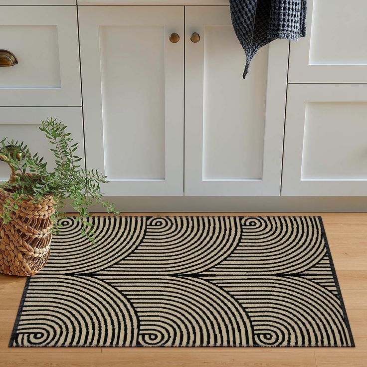 a black and white area rug in front of a kitchen counter with a potted plant