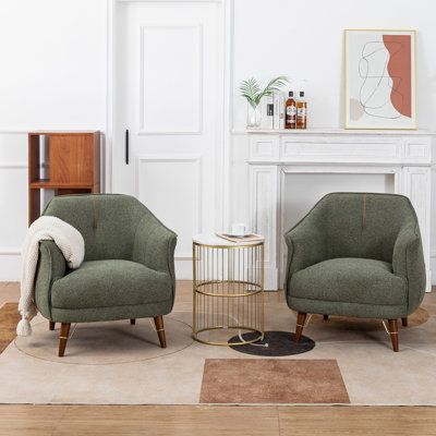 two green chairs sitting next to each other on top of a rug in front of a fireplace