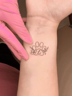 a woman's wrist with a dog paw tattoo on the left side of her arm