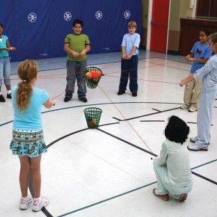 a group of young children standing around a basketball court