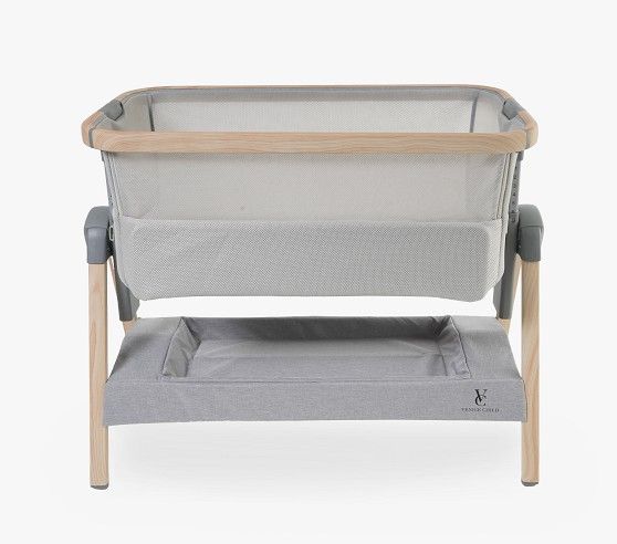 a baby crib with grey fabric and wooden frame, sitting on a white background