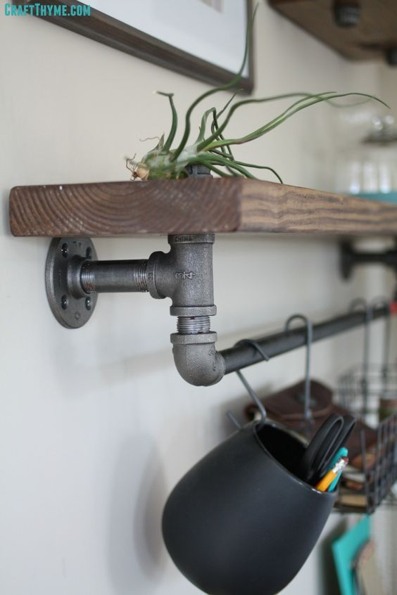 a potted plant sitting on top of a wooden shelf next to a metal pipe