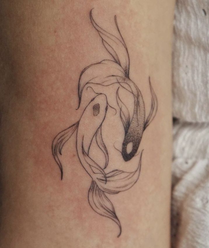 a black and white photo of a fish tattoo on the leg, with water swirling around it