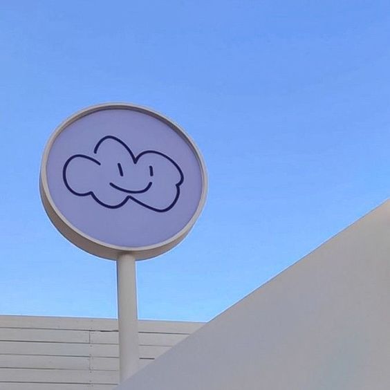 a white sign with a smiley face drawn on it's side next to a building