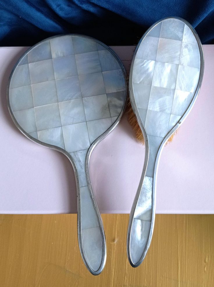 two silver spoons sitting next to each other on top of a wooden tablecloth