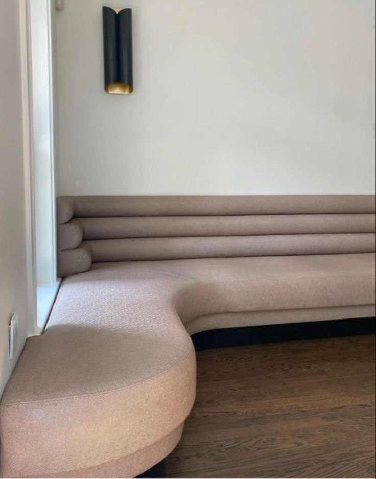 a corner couch with two lamps on the wall