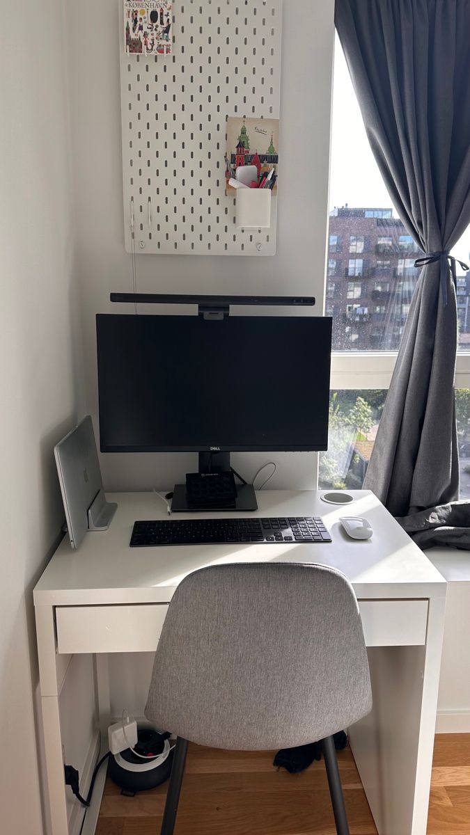 a desk with a computer on it in front of a window