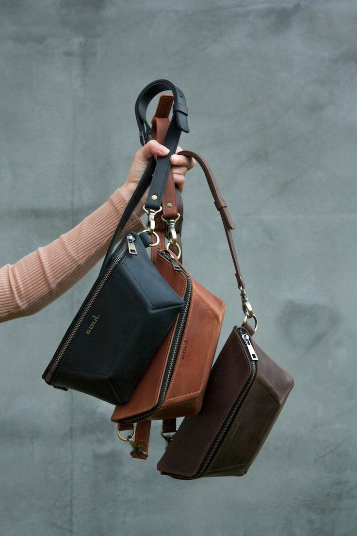 a person holding three different purses in their hands