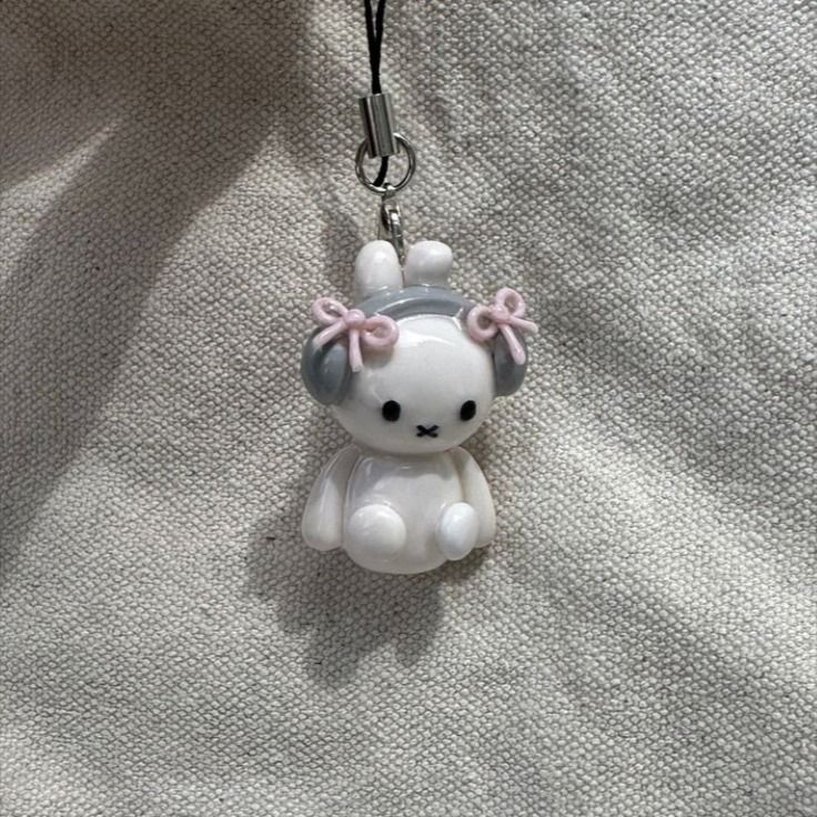 a keychain with a white and pink teddy bear on it's side