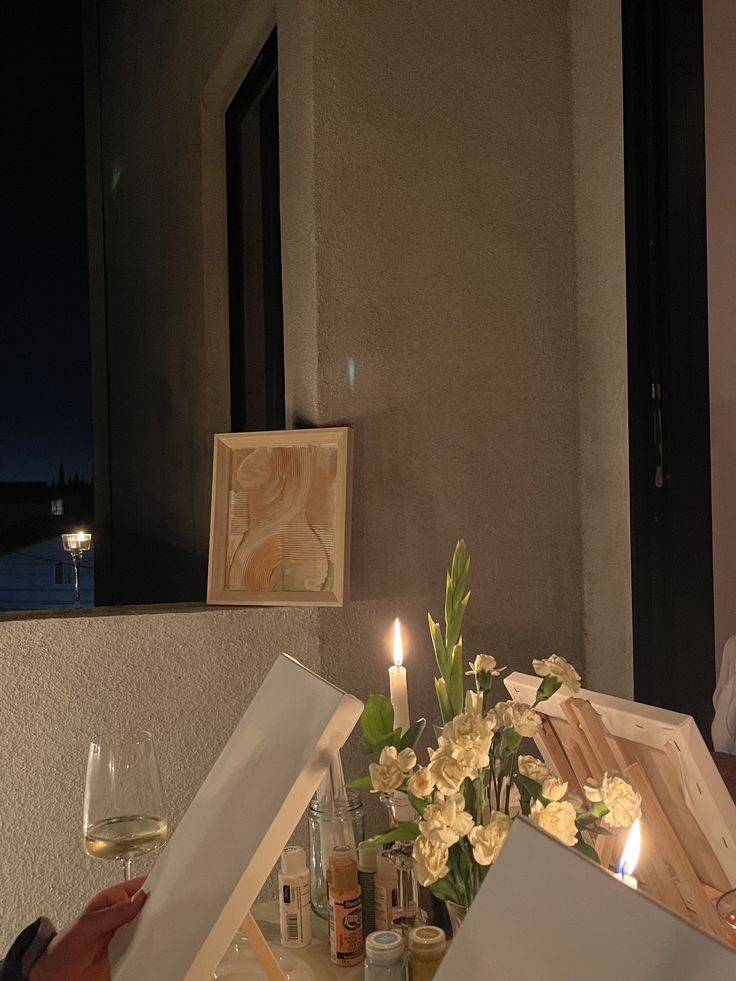 a table with flowers and candles on it in front of a window that is lit