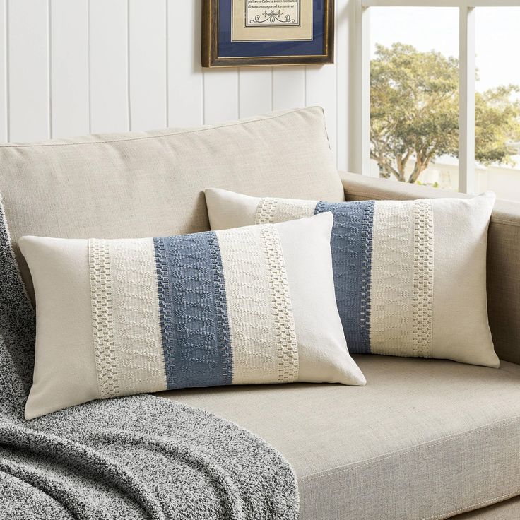 two pillows sitting on top of a couch next to a window