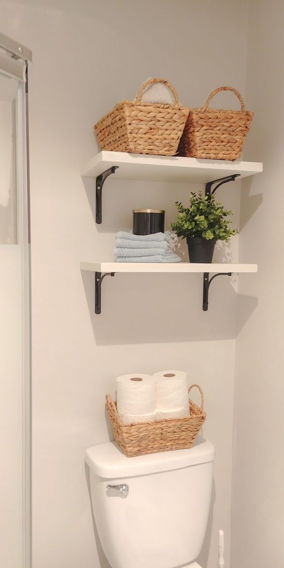 a white toilet sitting in a bathroom next to a shelf filled with towels and baskets