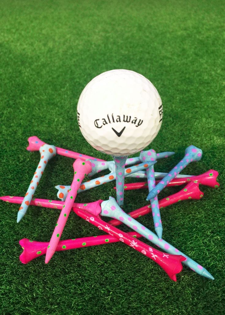 a golf ball sitting on top of a pile of pink and blue tees