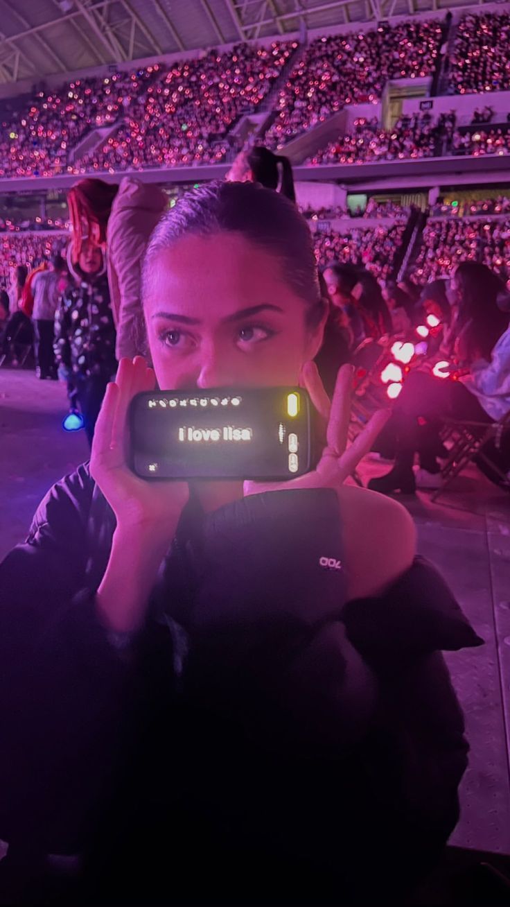 a woman taking a photo with her cell phone in front of an audience at a sporting event