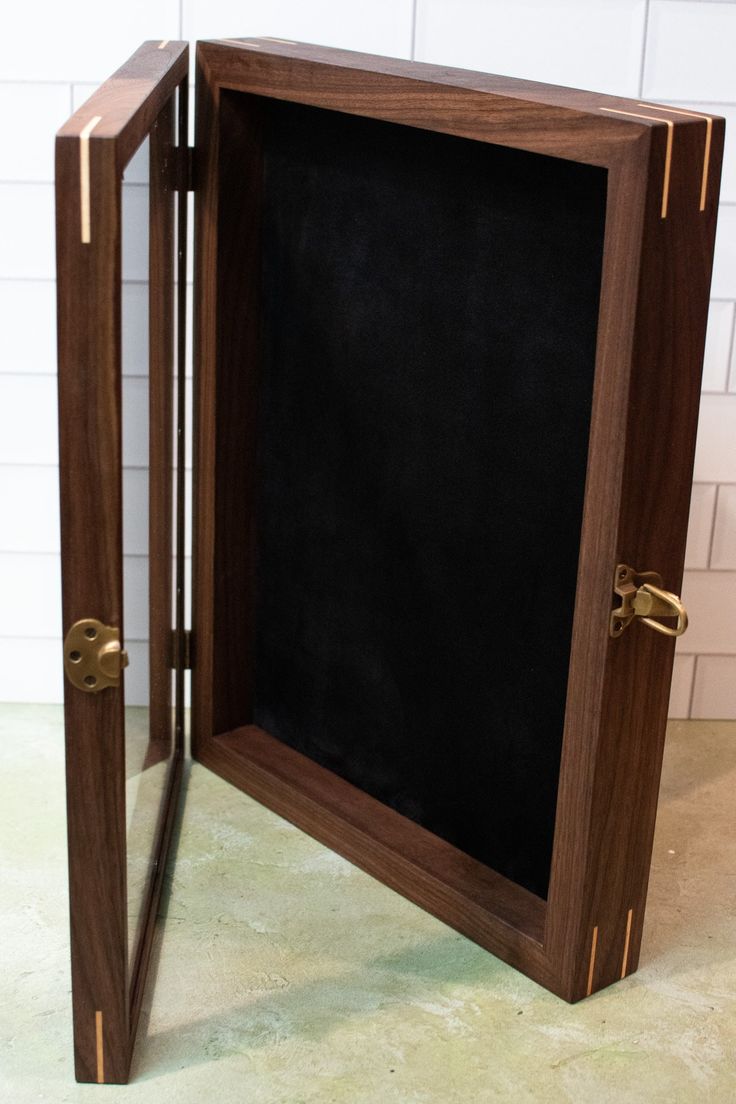 an open wooden box with a chalk board in the middle and gold trim around it